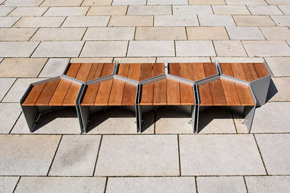 Modularer Holz- und Metalltisch in Pentagonform auf gepflastertem Untergrund.